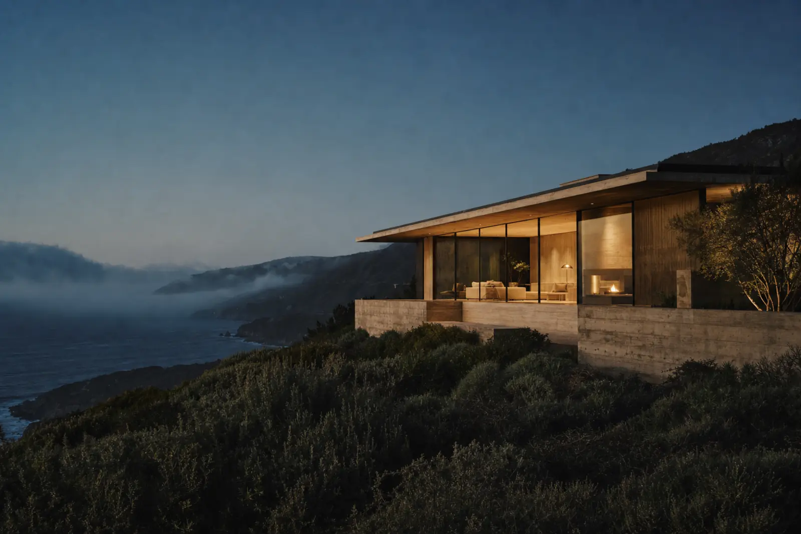 Tidewater House: a board-formed concrete and glass house on a Big Sur cliff at dusk, fog and dark ocean below.